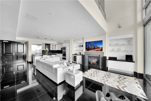 living area with visible vents, dark tile patterned flooring, a high end fireplace, and built in shelves