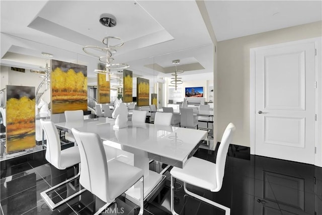 dining area with an inviting chandelier, visible vents, and a raised ceiling