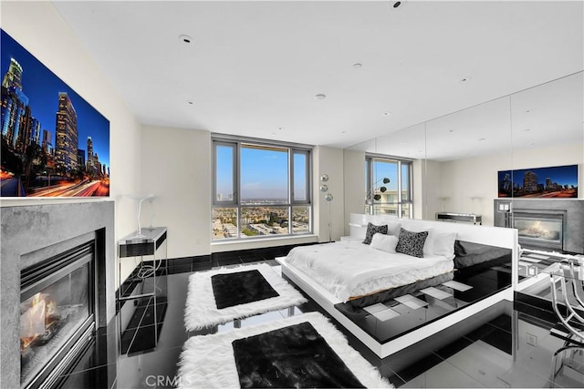 tiled bedroom featuring multiple windows and a glass covered fireplace