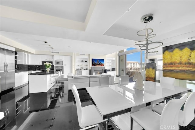 tiled dining area featuring a sink, an inviting chandelier, a raised ceiling, and visible vents