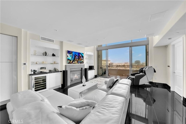 living area with expansive windows, built in shelves, a glass covered fireplace, baseboards, and visible vents