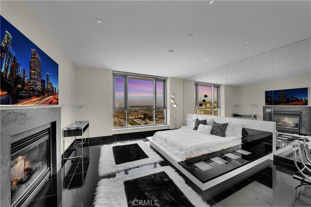 bedroom with tile patterned flooring and a glass covered fireplace