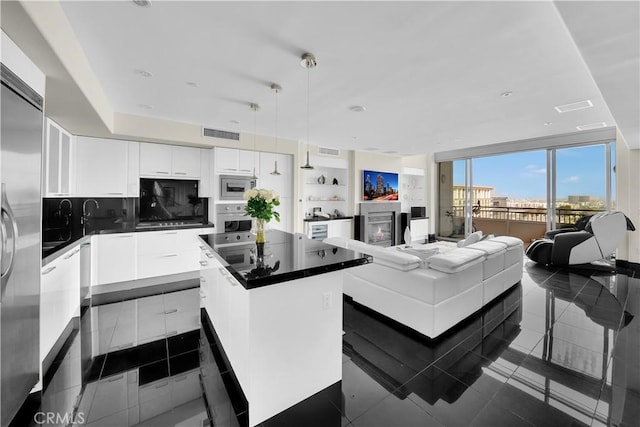 kitchen featuring a kitchen island, built in appliances, white cabinets, dark countertops, and visible vents