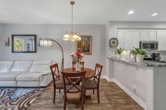 dining area with dark hardwood / wood-style floors and a notable chandelier