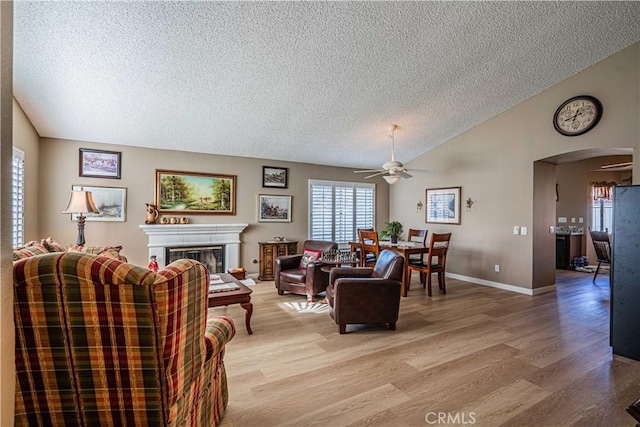 living room featuring ceiling fan, light hardwood / wood-style floors, a textured ceiling, and vaulted ceiling