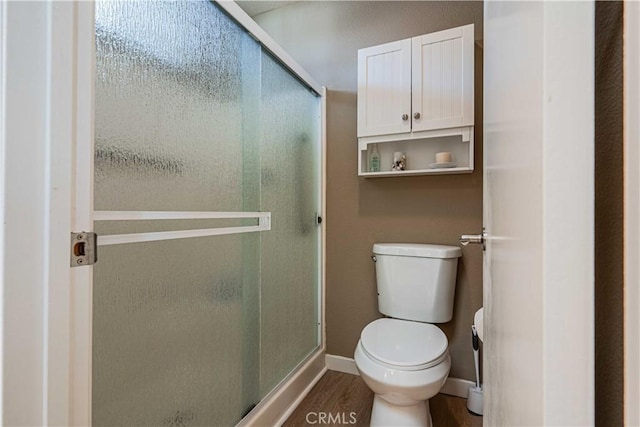 bathroom featuring hardwood / wood-style flooring, an enclosed shower, and toilet