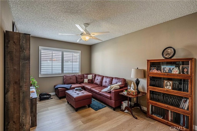 living room featuring light hardwood / wood-style floors, a textured ceiling, and ceiling fan