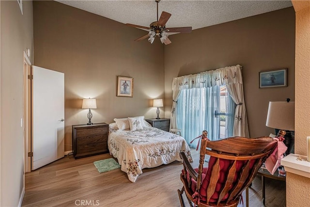 bedroom with a textured ceiling, ceiling fan, and light hardwood / wood-style flooring