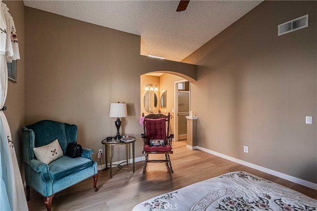 sitting room with light wood-type flooring, a textured ceiling, and vaulted ceiling