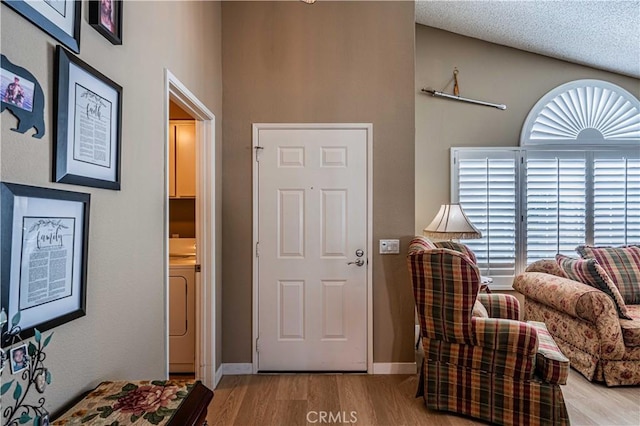 living area with a textured ceiling, wood-type flooring, and washer / clothes dryer