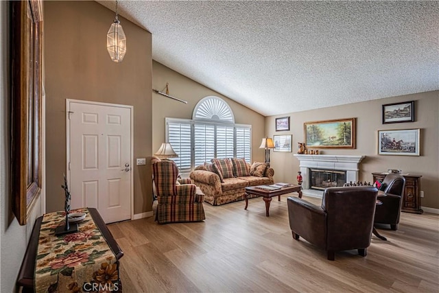 living room with light wood-type flooring, vaulted ceiling, and a textured ceiling