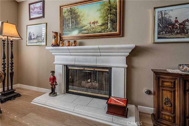 interior details featuring hardwood / wood-style flooring and a tiled fireplace