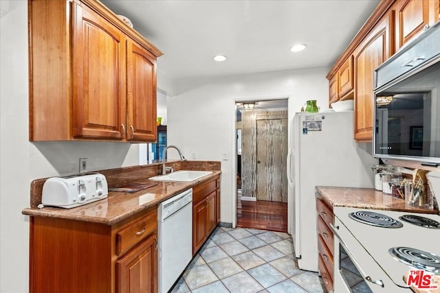 kitchen with light tile patterned floors, sink, stone countertops, and white appliances