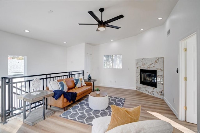 living room with ceiling fan, a fireplace, and light hardwood / wood-style flooring