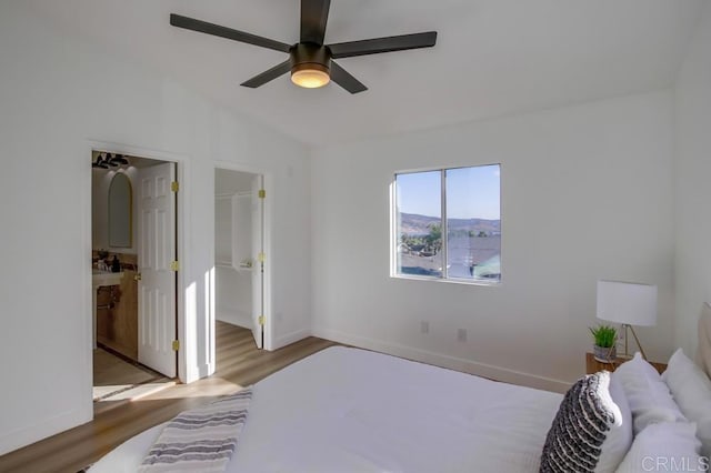 bedroom featuring ceiling fan, hardwood / wood-style floors, ensuite bathroom, and vaulted ceiling