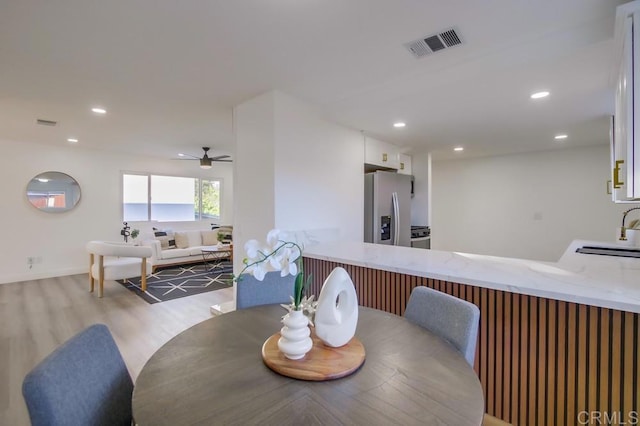 dining space with ceiling fan, sink, and light hardwood / wood-style flooring