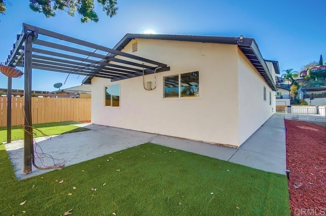 view of side of home featuring a patio area and a lawn