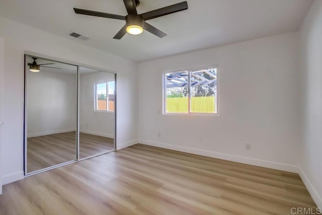 unfurnished bedroom with ceiling fan, a closet, and light wood-type flooring