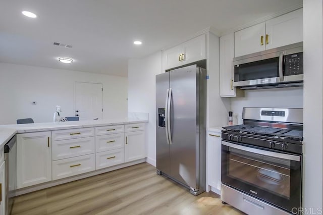 kitchen featuring light wood-type flooring, kitchen peninsula, stainless steel appliances, and white cabinetry