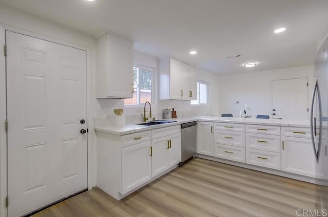 kitchen featuring stainless steel dishwasher, sink, white cabinetry, and light hardwood / wood-style floors