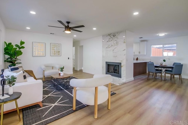 living room featuring ceiling fan, light hardwood / wood-style floors, and a fireplace