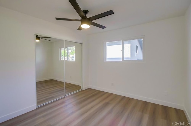 unfurnished bedroom featuring ceiling fan, a closet, and hardwood / wood-style floors