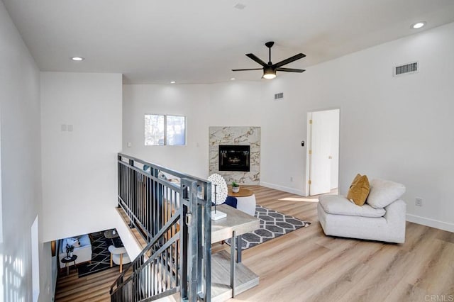 living room featuring ceiling fan, wood-type flooring, and a premium fireplace