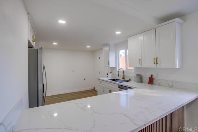 kitchen with light stone counters, sink, white cabinets, and stainless steel appliances