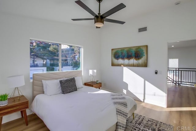 bedroom with ceiling fan, hardwood / wood-style flooring, and multiple windows