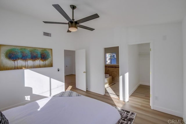 unfurnished bedroom featuring a spacious closet, ceiling fan, ensuite bath, a closet, and light hardwood / wood-style flooring