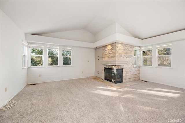 unfurnished living room featuring a fireplace, light carpet, vaulted ceiling, and plenty of natural light