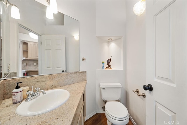 bathroom with wood-type flooring, vanity, and toilet