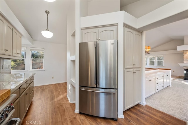 kitchen featuring lofted ceiling, decorative light fixtures, cream cabinetry, stainless steel fridge, and a wealth of natural light