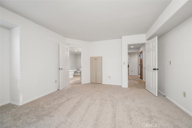 unfurnished bedroom featuring light carpet and ensuite bathroom