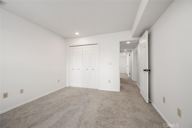 unfurnished bedroom with a closet and light colored carpet