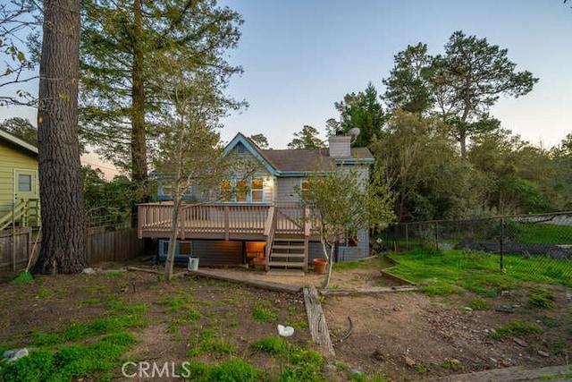 back house at dusk featuring a wooden deck