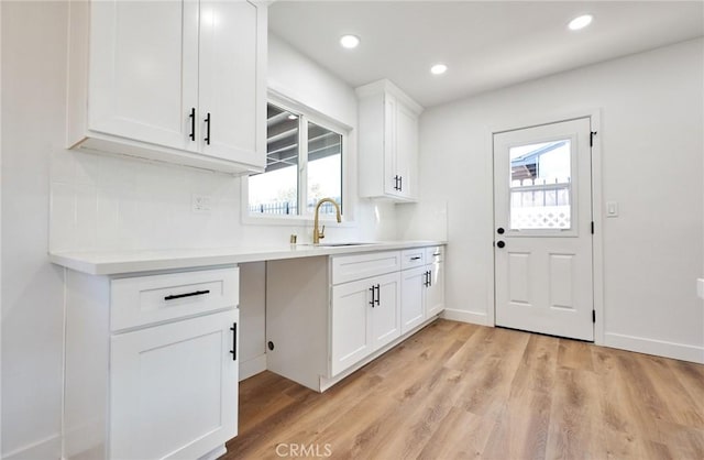 kitchen featuring light wood-type flooring, white cabinets, and sink