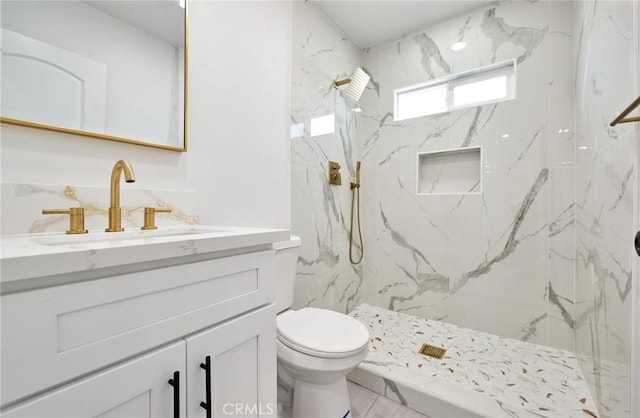 bathroom featuring toilet, vanity, and tiled shower