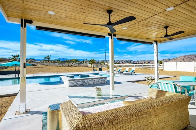 view of swimming pool with ceiling fan, a patio area, a mountain view, and an in ground hot tub