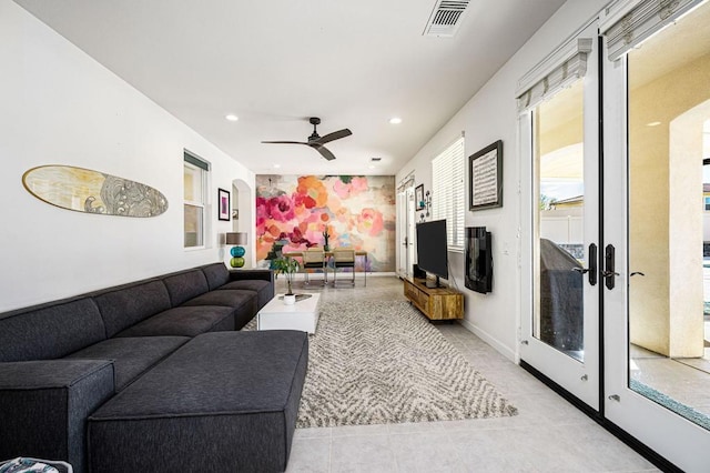 tiled living room with ceiling fan and french doors