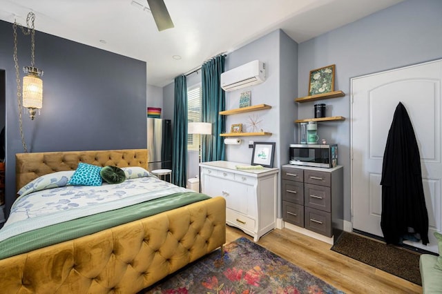 bedroom featuring ceiling fan, light hardwood / wood-style flooring, and a wall unit AC