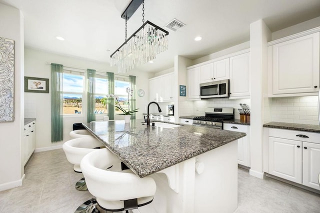 kitchen with white cabinetry, sink, stainless steel appliances, and a center island with sink