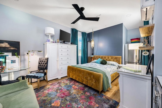 bedroom featuring ceiling fan, stainless steel fridge, and hardwood / wood-style floors