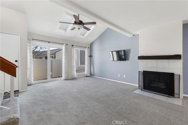 unfurnished living room featuring ceiling fan, vaulted ceiling with beams, a tile fireplace, and light colored carpet