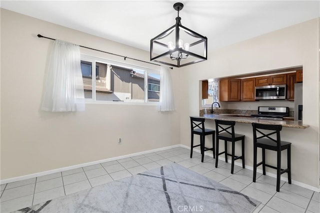 kitchen with hanging light fixtures, light tile patterned floors, a kitchen bar, and stainless steel appliances