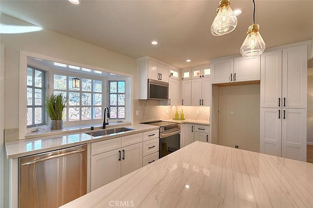 kitchen with appliances with stainless steel finishes, sink, hanging light fixtures, and white cabinets