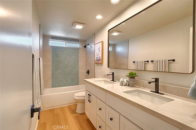 full bathroom featuring tiled shower / bath, wood-type flooring, vanity, and toilet