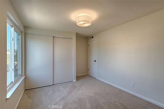 unfurnished bedroom featuring light carpet and a closet