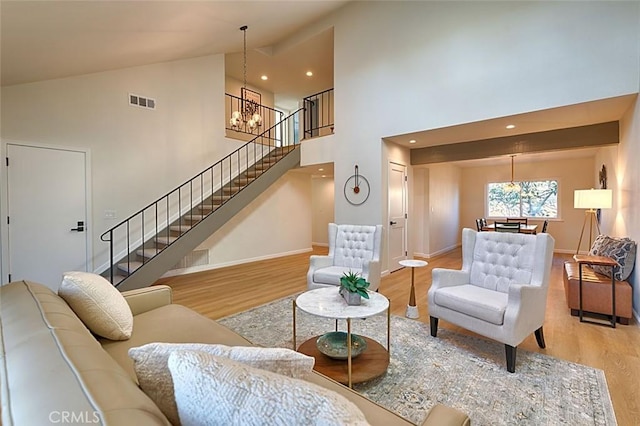 living room with an inviting chandelier, high vaulted ceiling, and light wood-type flooring