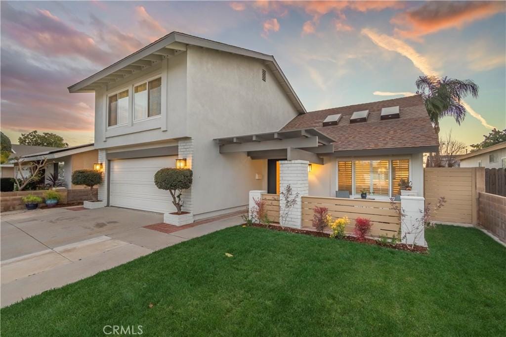 view of front of property with driveway, a garage, fence, a front lawn, and stucco siding